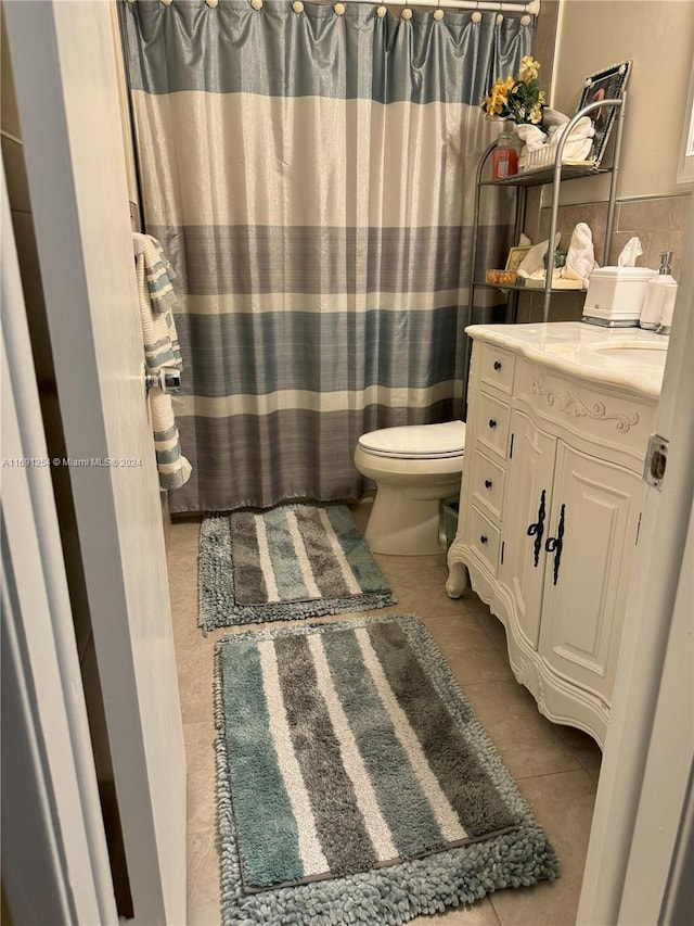 bathroom with vanity, tile patterned flooring, toilet, and tasteful backsplash