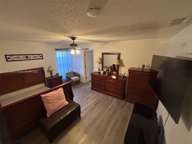 bedroom featuring ceiling fan, wood-type flooring, and a textured ceiling