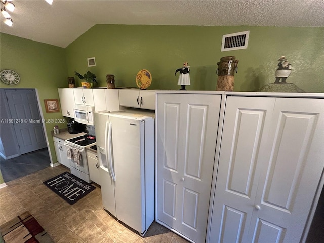 kitchen with white appliances, lofted ceiling, a textured ceiling, and white cabinets