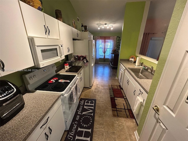 kitchen with white appliances, track lighting, sink, and white cabinets