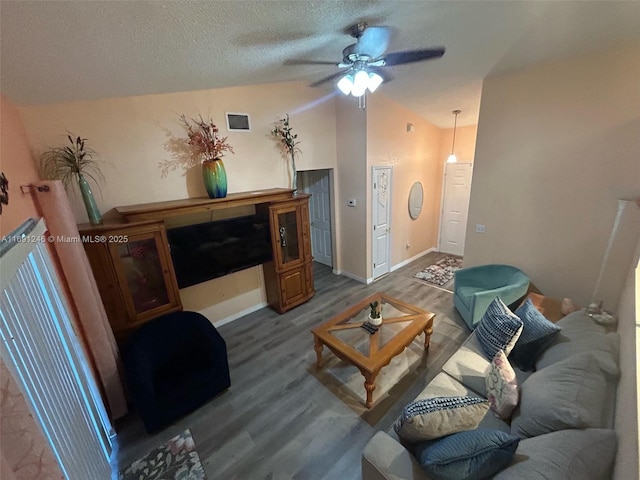 living room with ceiling fan, lofted ceiling, hardwood / wood-style floors, and a textured ceiling