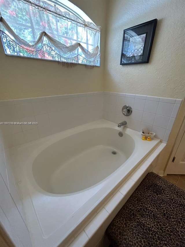 bathroom with tiled tub and tile patterned floors