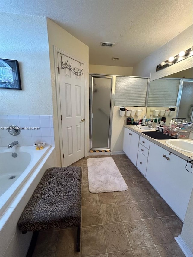 bathroom featuring vanity, shower with separate bathtub, and a textured ceiling