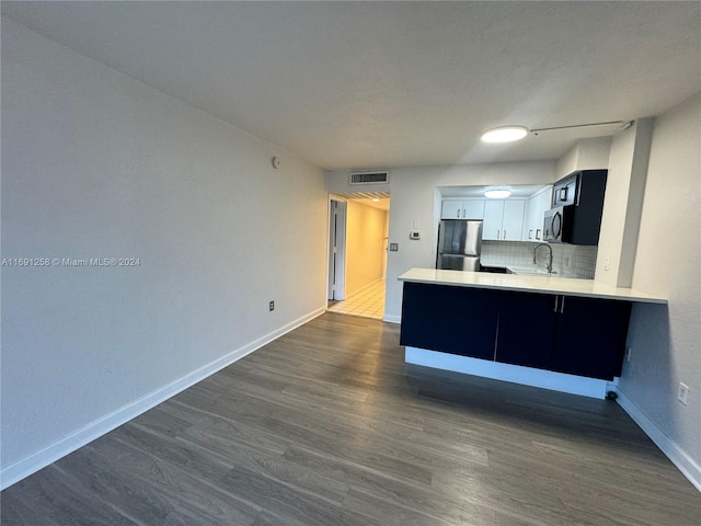 kitchen with dark hardwood / wood-style flooring, kitchen peninsula, stainless steel appliances, and white cabinets