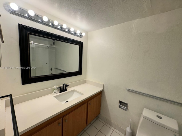 bathroom featuring tile patterned floors, walk in shower, vanity, a textured ceiling, and toilet