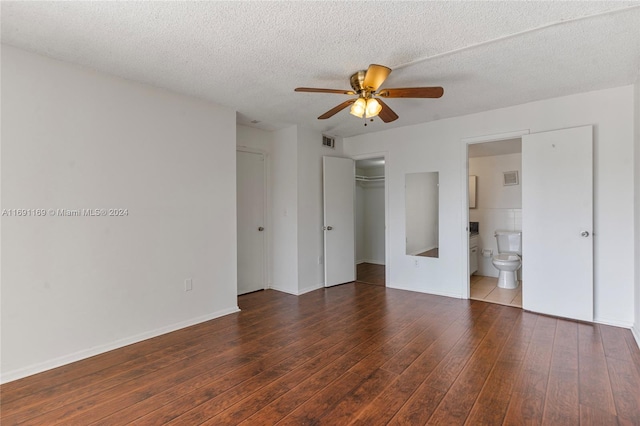 unfurnished bedroom with ceiling fan, ensuite bath, a textured ceiling, and dark hardwood / wood-style flooring