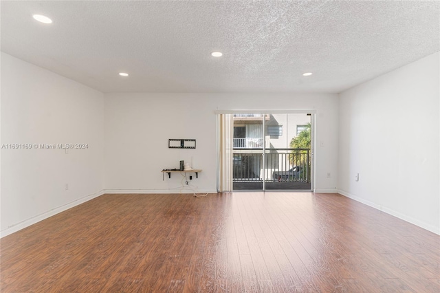 empty room with a textured ceiling and hardwood / wood-style flooring