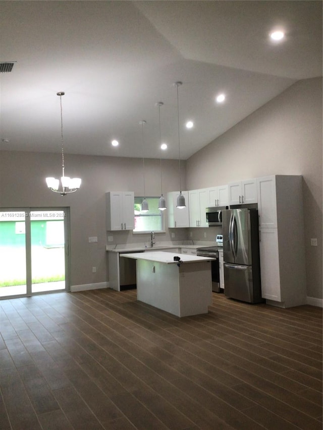 kitchen with pendant lighting, lofted ceiling, white cabinets, a kitchen island, and stainless steel appliances