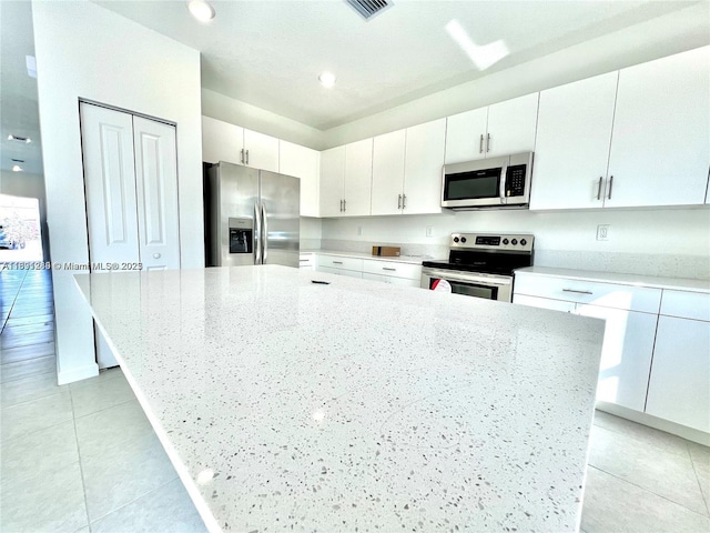 kitchen with light tile patterned floors, stainless steel appliances, and white cabinetry