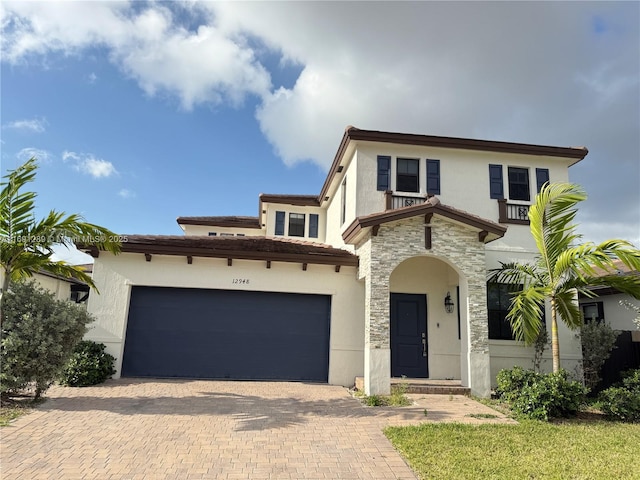 mediterranean / spanish house featuring decorative driveway, stone siding, and stucco siding
