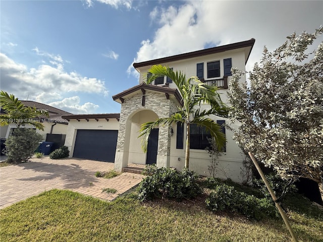 mediterranean / spanish house featuring a garage, decorative driveway, stucco siding, and stone siding