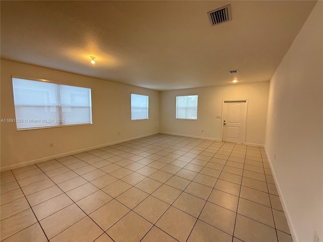 spare room with baseboards, light tile patterned flooring, and visible vents