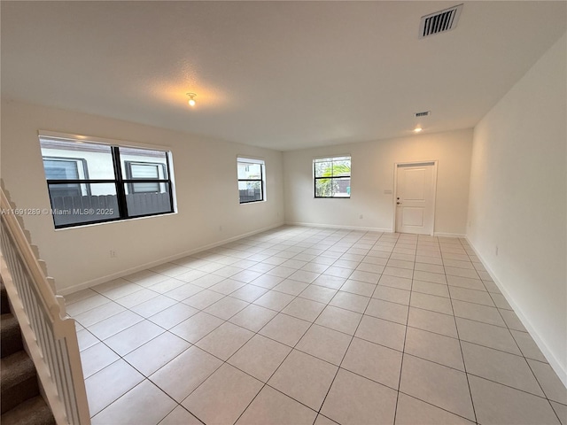 unfurnished room featuring light tile patterned floors, baseboards, stairs, and visible vents