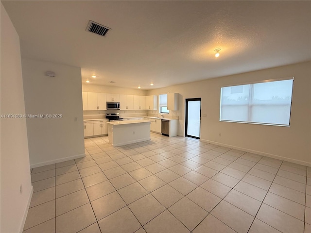 kitchen featuring appliances with stainless steel finishes, light countertops, a center island, recessed lighting, and light tile patterned floors
