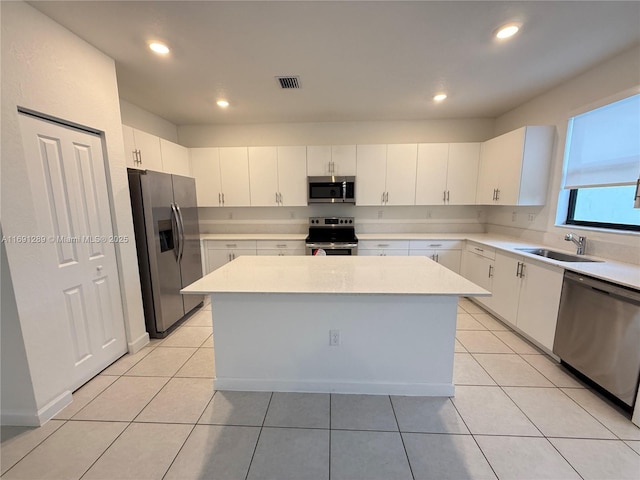 kitchen with visible vents, a kitchen island, light countertops, a sink, and stainless steel appliances