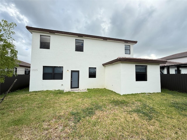 back of house featuring fence, stucco siding, and a yard