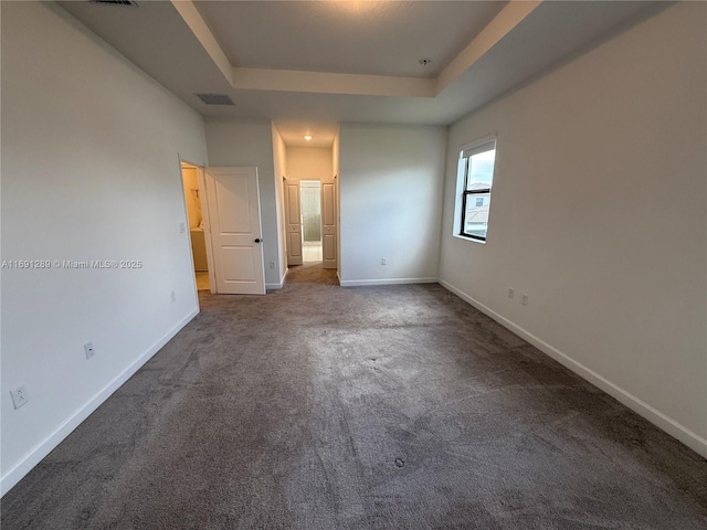 unfurnished bedroom featuring baseboards, carpet, and a raised ceiling