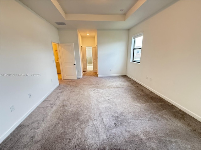 unfurnished bedroom featuring carpet floors, a raised ceiling, baseboards, and visible vents