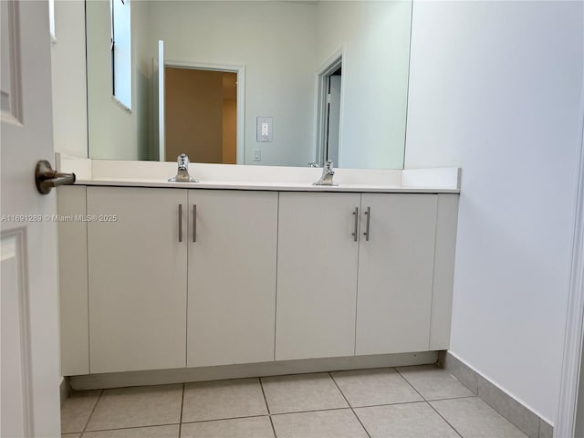 bathroom featuring tile patterned flooring, a sink, baseboards, and double vanity
