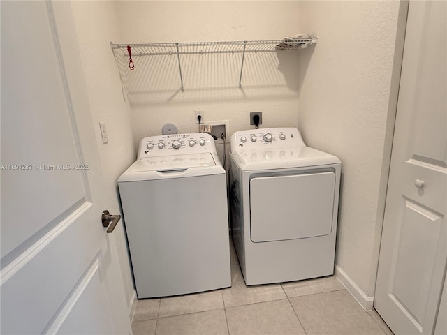clothes washing area featuring independent washer and dryer, light tile patterned flooring, and laundry area