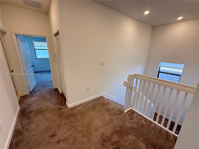 corridor featuring visible vents, baseboards, an upstairs landing, carpet flooring, and recessed lighting