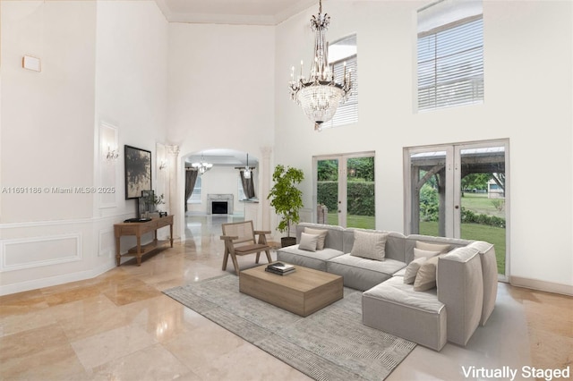 living room with crown molding, a fireplace, french doors, and a chandelier