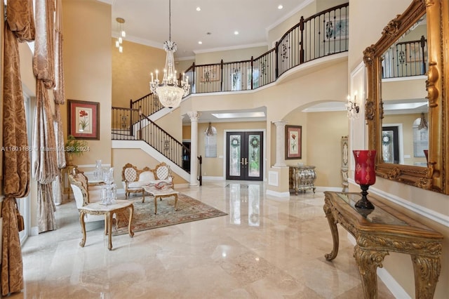 entrance foyer with decorative columns, a high ceiling, french doors, crown molding, and a chandelier