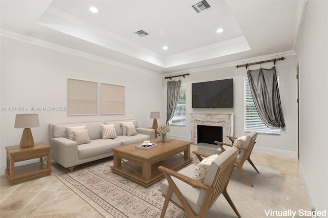 living room featuring crown molding, a tray ceiling, and a high end fireplace