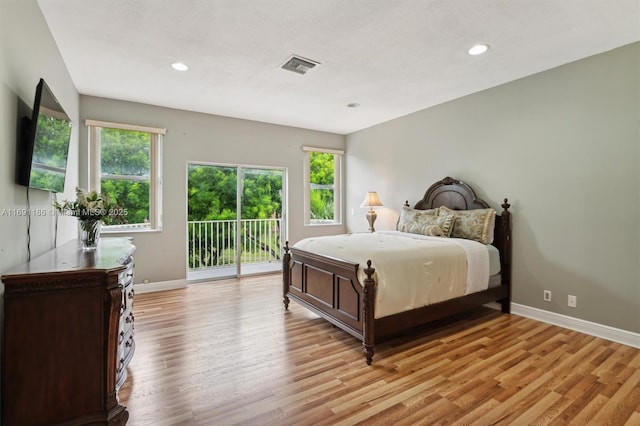 bedroom featuring multiple windows, access to exterior, and light hardwood / wood-style flooring