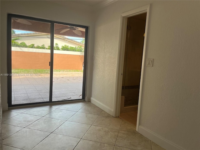 spare room with ceiling fan, crown molding, and light tile patterned floors