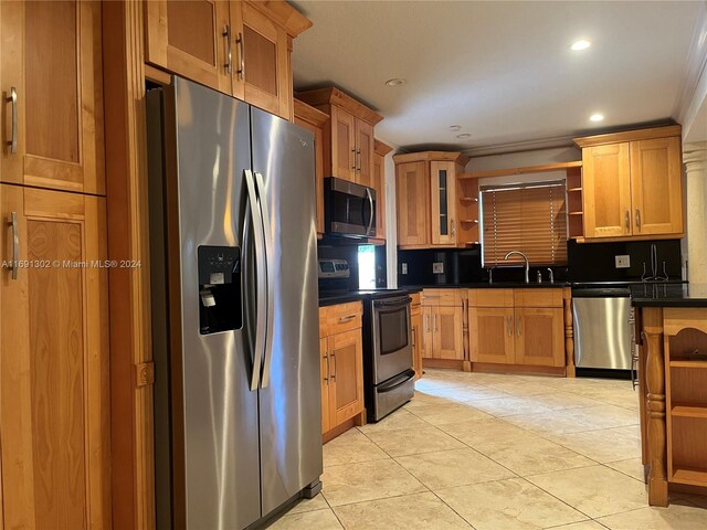 kitchen with crown molding, stainless steel appliances, light tile patterned floors, sink, and decorative backsplash