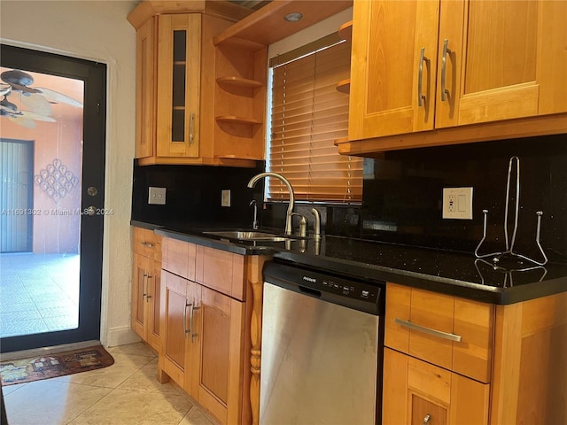 kitchen featuring tasteful backsplash, dark stone counters, light tile patterned floors, sink, and stainless steel dishwasher