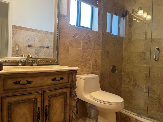 bathroom featuring a shower with door, vanity, toilet, and tile walls