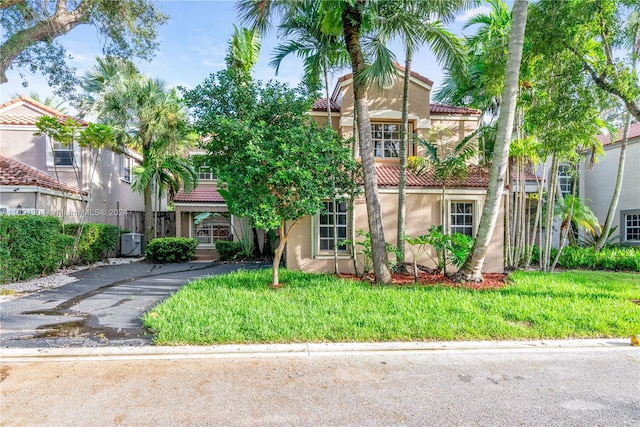 mediterranean / spanish home with cooling unit and a front lawn