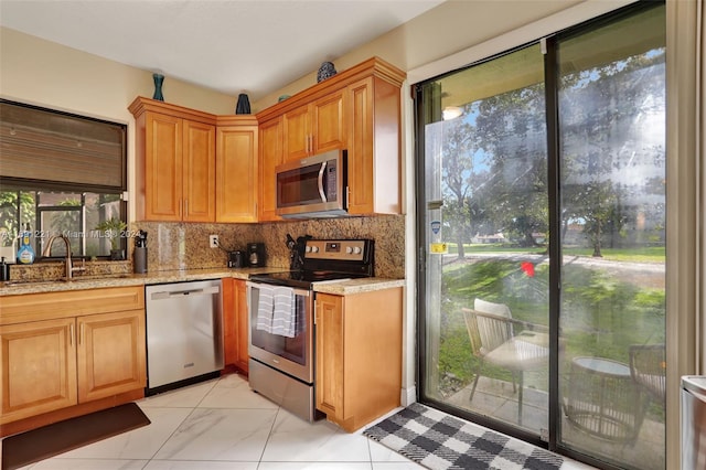 kitchen with decorative backsplash, sink, light stone counters, and stainless steel appliances