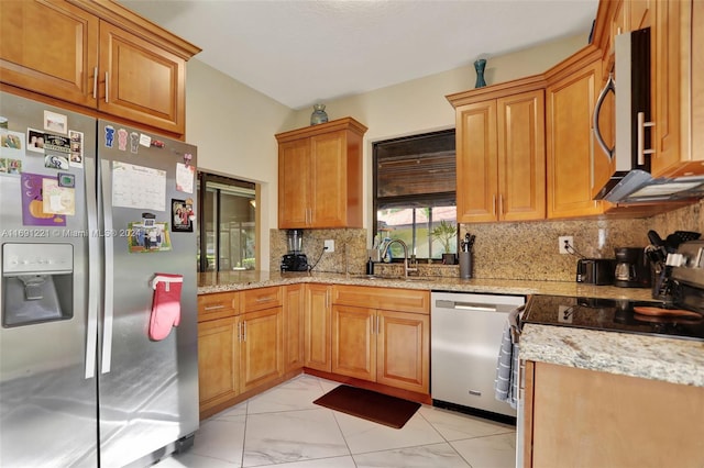 kitchen featuring stainless steel appliances, light stone countertops, sink, and backsplash