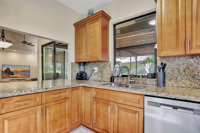 kitchen with backsplash, light stone countertops, sink, stainless steel dishwasher, and ceiling fan