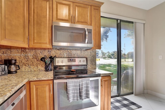 kitchen featuring a wealth of natural light, stainless steel appliances, light tile patterned flooring, and tasteful backsplash