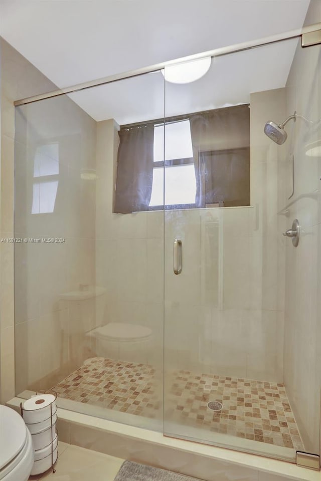 bathroom with toilet, tile patterned floors, and walk in shower