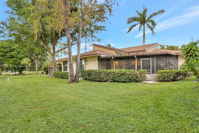 rear view of house featuring a lawn and a sunroom