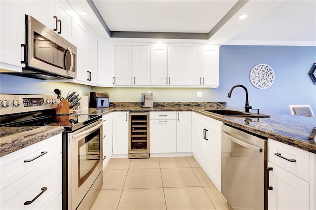 kitchen with white cabinets, appliances with stainless steel finishes, and beverage cooler