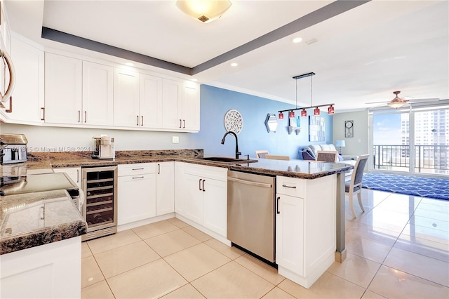 kitchen featuring sink, kitchen peninsula, stainless steel dishwasher, beverage cooler, and pendant lighting