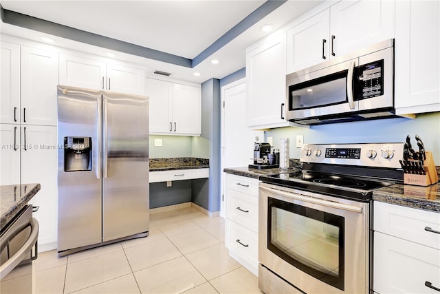 kitchen with white cabinets, dark stone countertops, light tile patterned floors, and appliances with stainless steel finishes