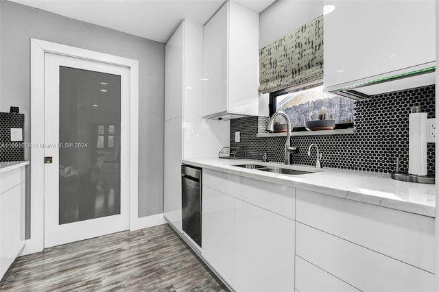 kitchen featuring hardwood / wood-style floors, decorative backsplash, sink, light stone countertops, and white cabinetry