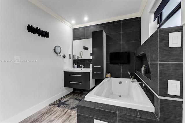 bathroom with vanity, hardwood / wood-style floors, ornamental molding, and tiled tub