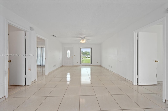 tiled spare room with a textured ceiling and ceiling fan