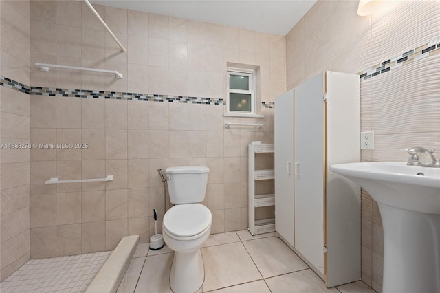 bathroom featuring tiled shower, tile patterned floors, toilet, and tile walls