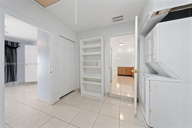 laundry area featuring stacked washer and dryer and light tile patterned floors