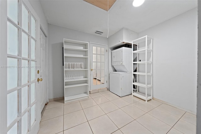 laundry room featuring light tile patterned flooring and stacked washer and clothes dryer