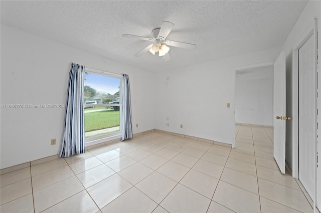 tiled empty room with ceiling fan and a textured ceiling